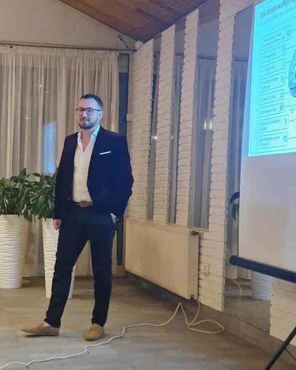 Robert Dobucki prowadzi prelekcję przy ekranie prezentacji.
