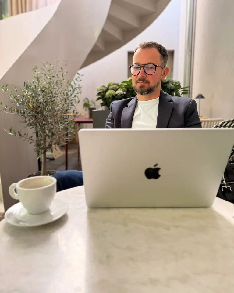 Robert Dobucki pracuje przy laptopie w jasnym wnętrzu.